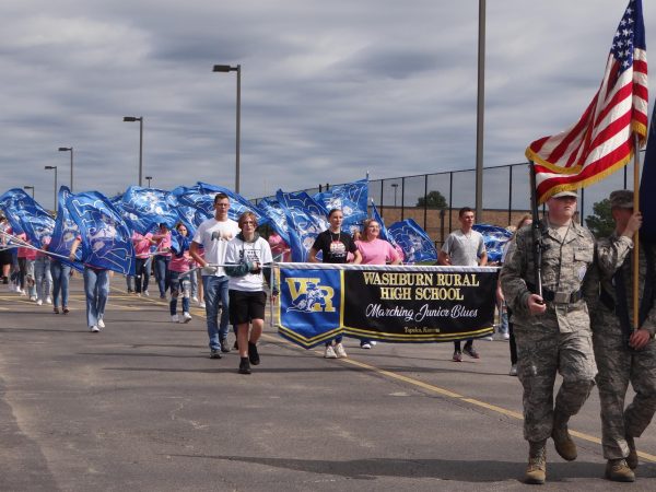 The band holds up a sign, starting the Homecoming Parade.