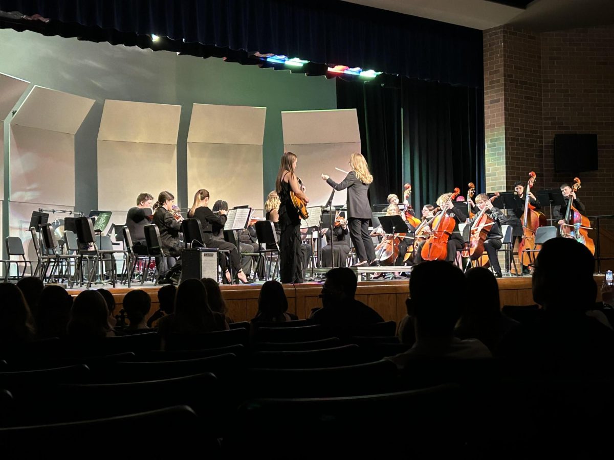 Concert orchestra playing their last song with guitarist, Megan Weis.